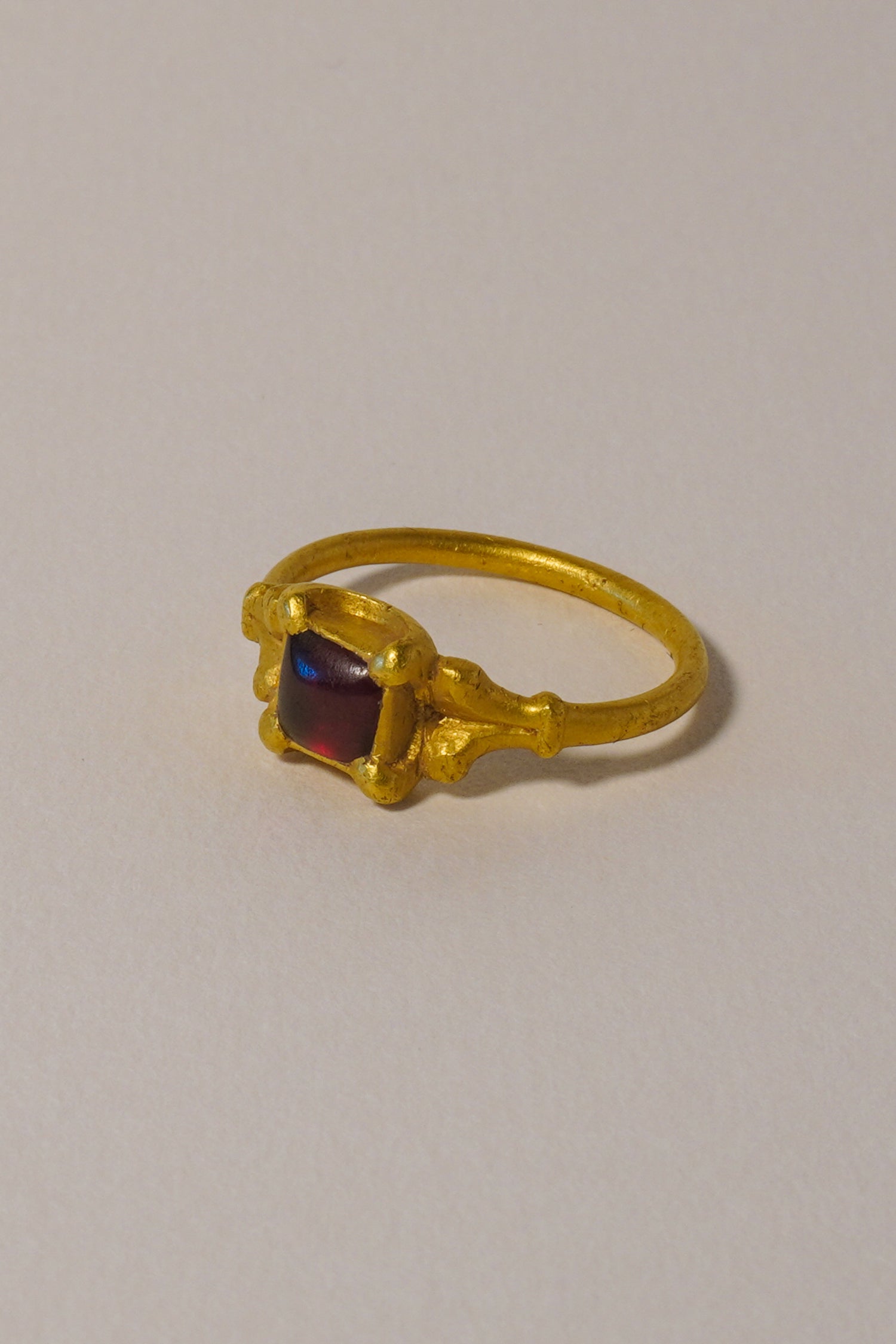 MEDIEVAL SOLID GOLD RING WITH GARNET CABOCHON, CARVED QUATREFOIL BEZEL. 15TH-16TH CENTURY AD
