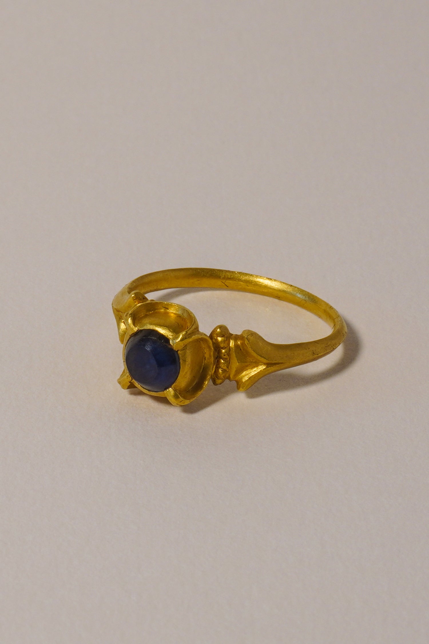 MEDIEVAL SOLID GOLD RING WITH SAPPHIRE, QUATREFOIL DETAIL AND CARVED BEZEL. 14TH-15TH CENTURY AD