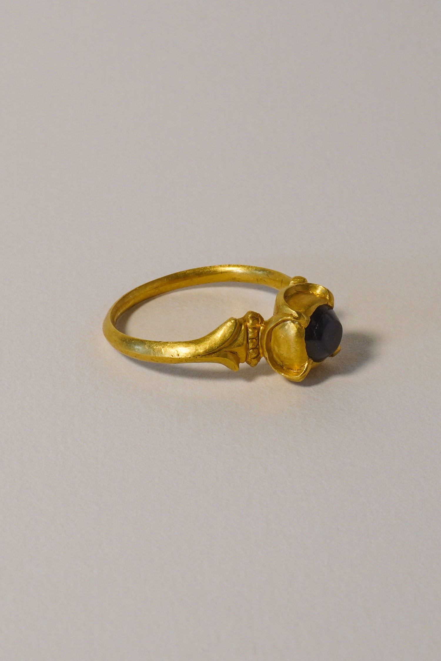 MEDIEVAL SOLID GOLD RING WITH SAPPHIRE, QUATREFOIL DETAIL AND CARVED BEZEL. 14TH-15TH CENTURY AD (RIGHT)