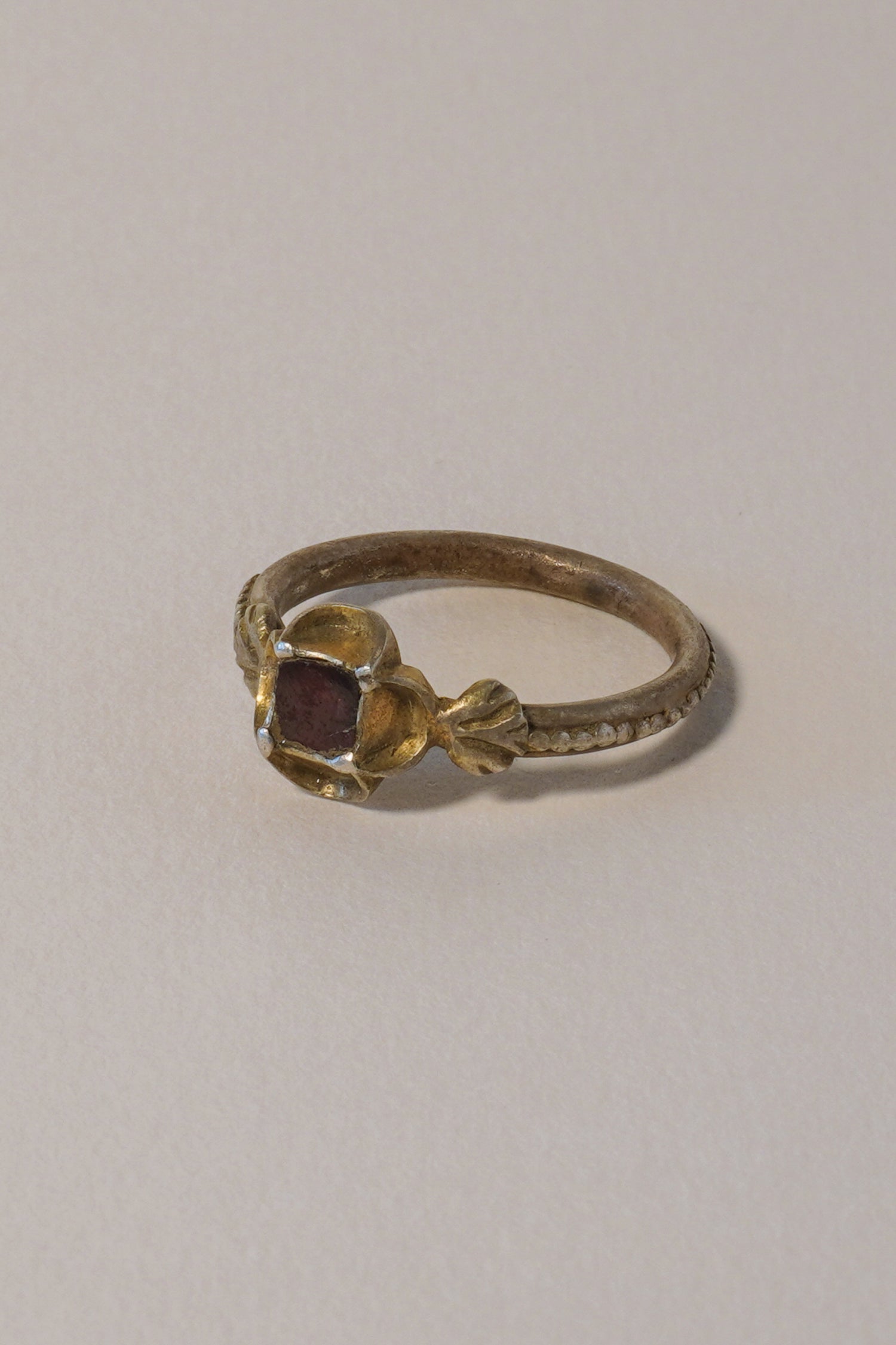MEDIEVAL SILVER GILT RING WITH GARNET, CARVED QUATREFOIL BEZEL. 15TH-16TH CENTURY AD