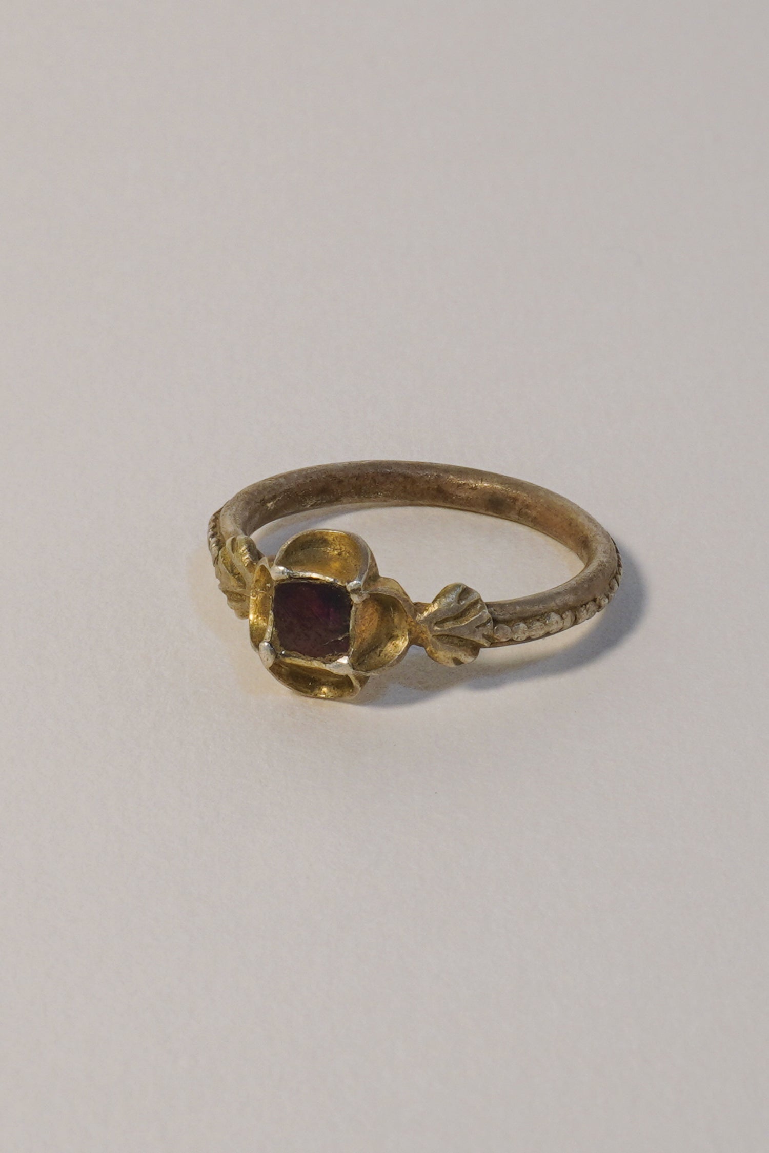 MEDIEVAL SILVER GILT RING WITH GARNET, CARVED QUATREFOIL BEZEL. 15TH-16TH CENTURY AD (LEFT VIEW)